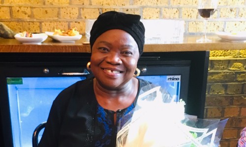 Local Age UK beneficiary, Agatha holding flowers smiling with joy