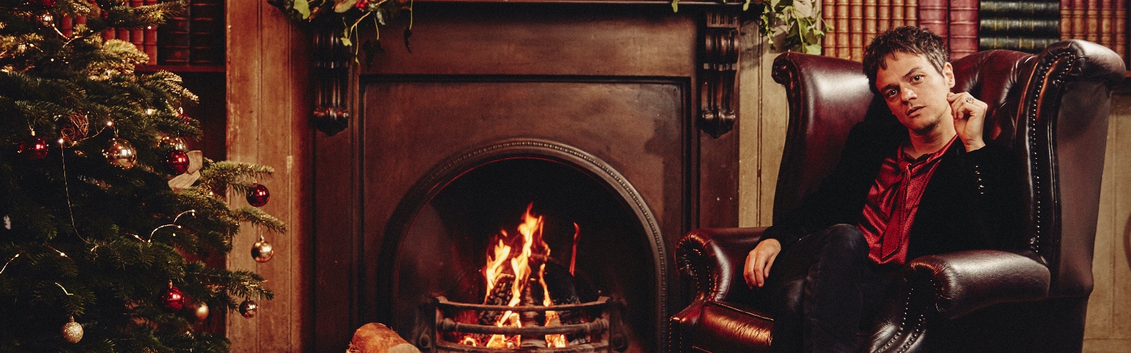 Singer-songwriter Jamie Cullum, sat in a chair next to a fireplace