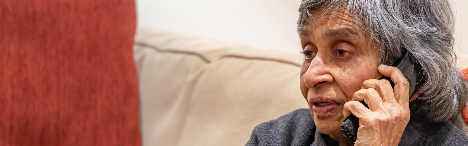 An older woman, looking concerned, speaking on the phone