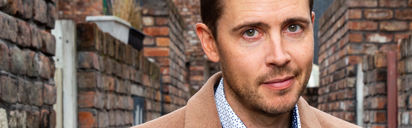 Actor Gareth Pierce, playing Todd Grimshaw on Coronation Street, stands in one of the street's red brick gulleys