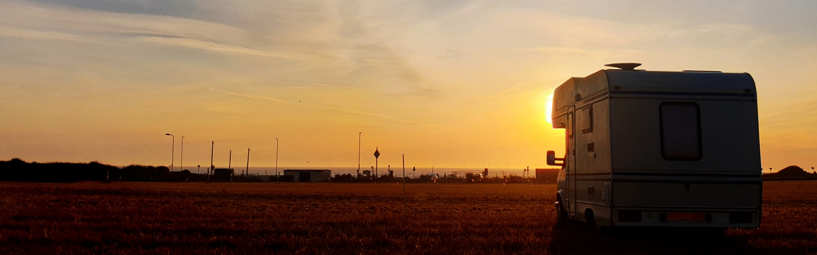 A motorhome, silhouetted against a sunset