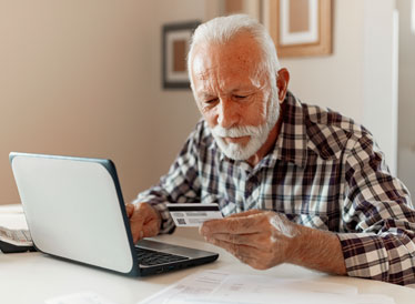 Man at laptop looking at bank card